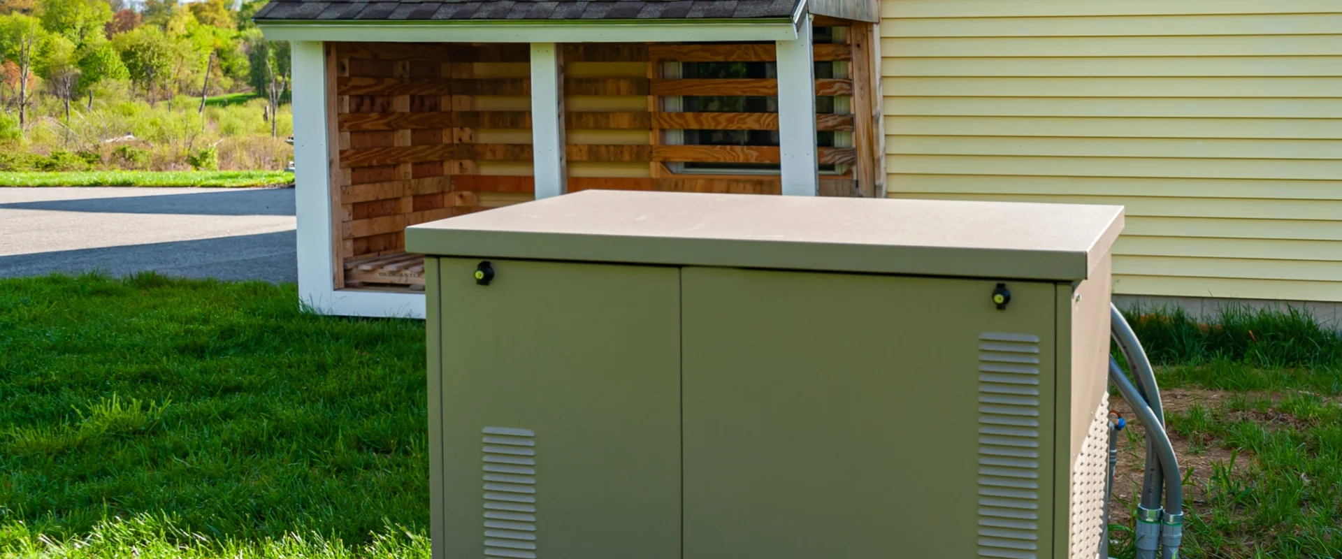 A residential standby generator on a concrete pad beside a house