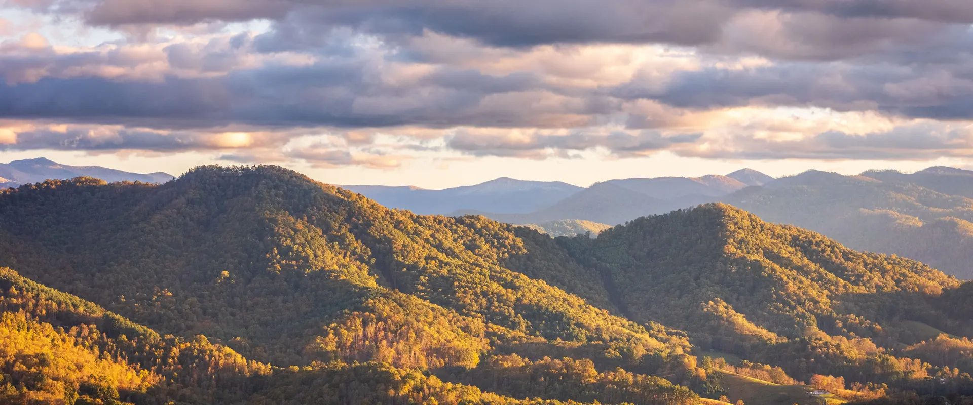 Forested ridgelines fading into haze at sunset