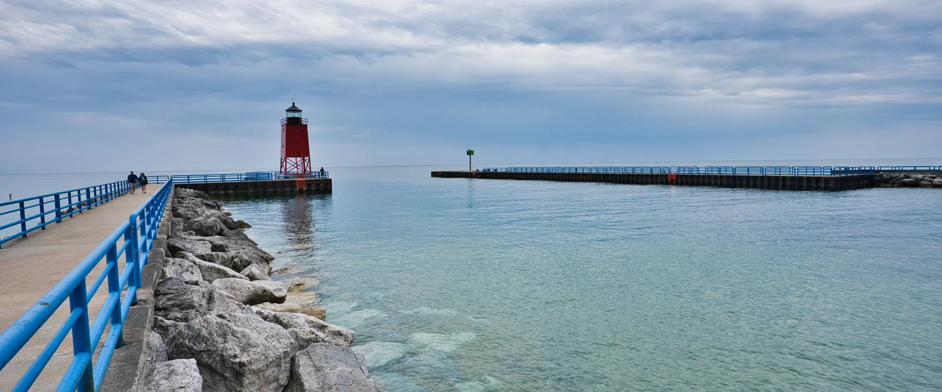 A pier lighthouse on a Great Lakes shoreline at sunset