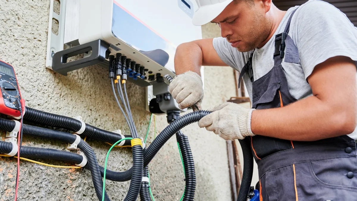 An electrician wiring a residential inverter and battery system